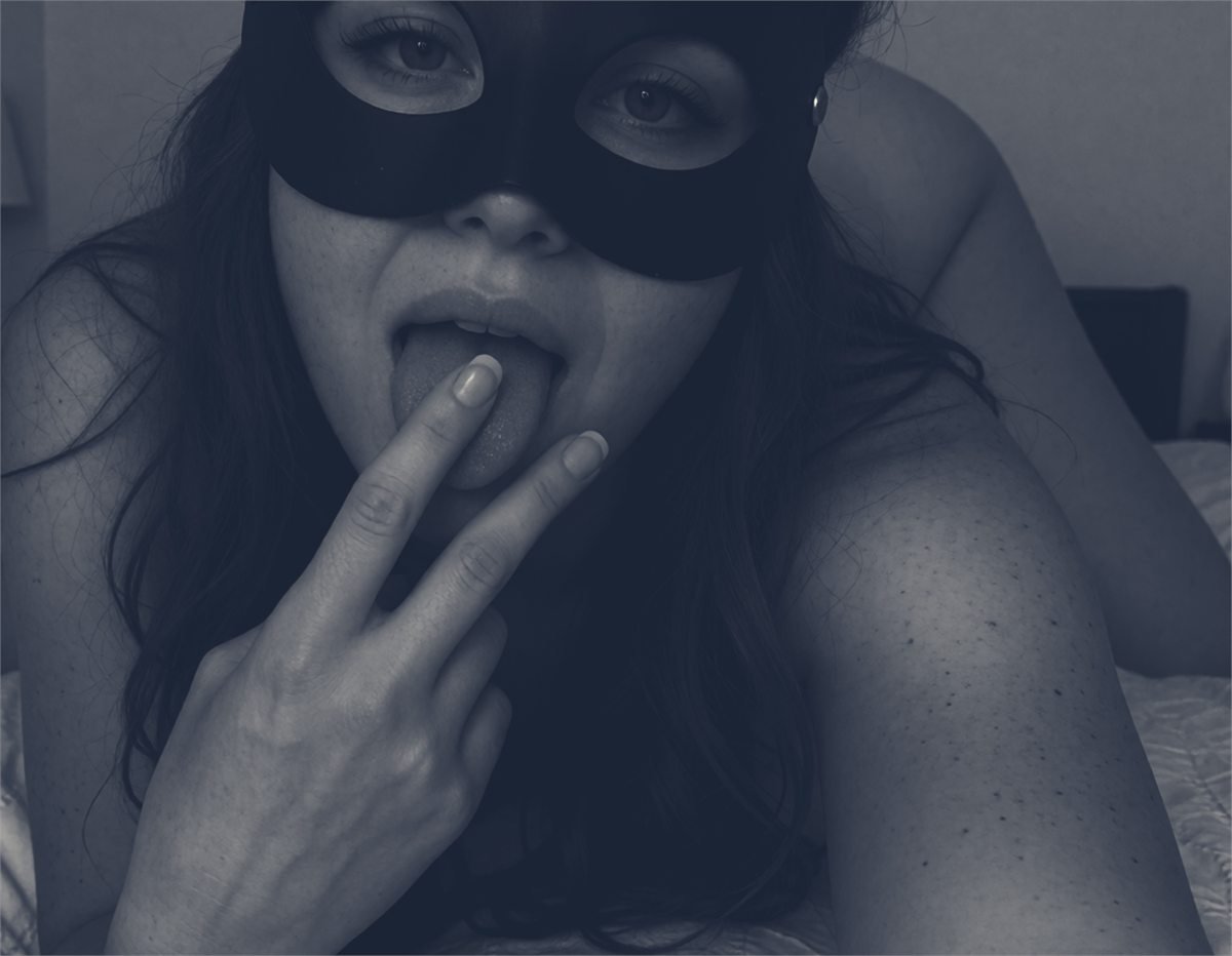 A masked performer in a dark intimate portrait