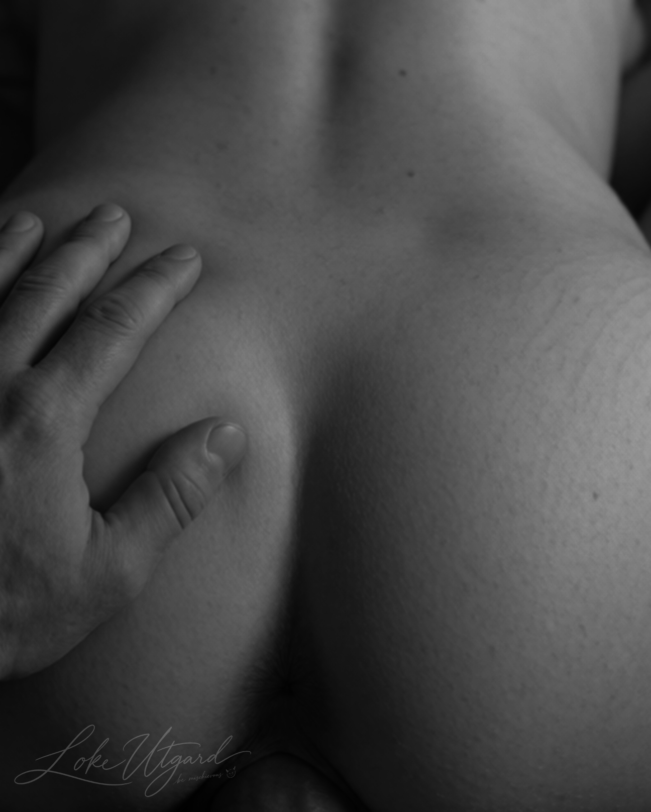 Monochrome close-up of a hand resting on a bare back.