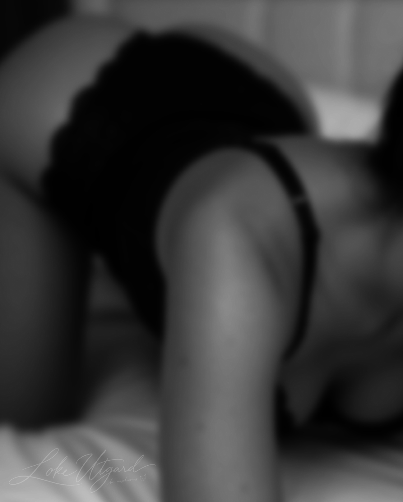 Soft-focus monochrome photograph of a woman reclining on a bed.
