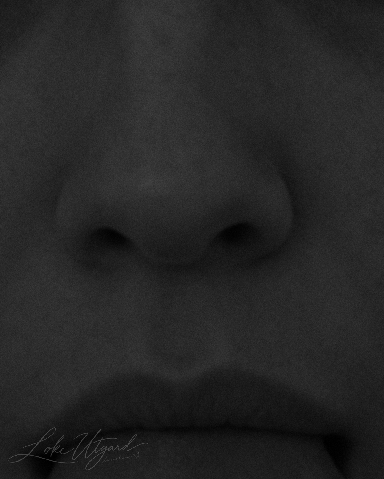 Monochrome close-up of a face, with the nose and lips in soft light.