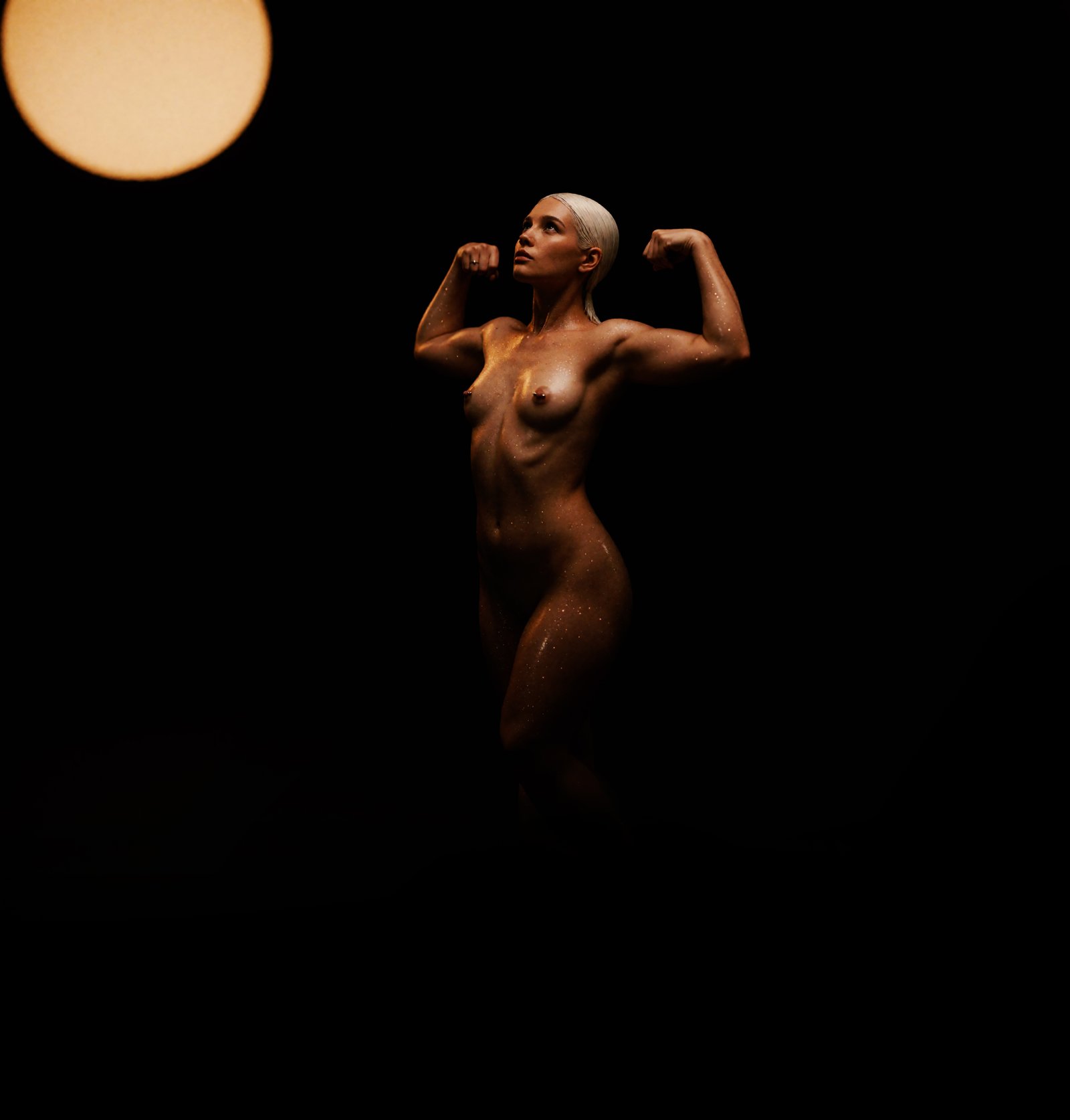 Joyce posing beneath a glowing orb in a dark studio portrait
