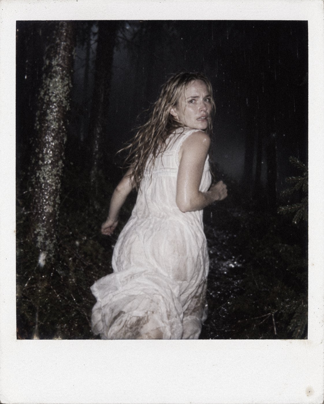 Nightmare series portrait of a woman looking back while running through a dark forest